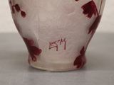 a white vase with red flowers on it sitting on a table