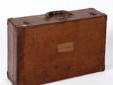 une valise marron posée sur une surface blanche