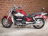 a red motorcycle that is parked in front of a brick wall