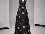 robe de soirée noire ornée de fleurs dorées, présentée sur un mannequin, avec un décolleté