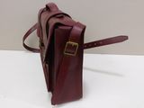a close up of a red leather bag on a white surface
