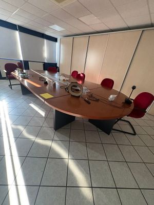 une photo d'une salle de réunion avec une longue table et des chaises rouges