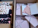 a cardboard box filled with baby clothes and other items