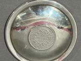 a silver plate with a coin in it on a table