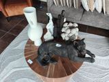 une statue représentant un chien couché sur une table, à côté d'un vase