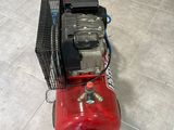 a red air compressor sitting on a tile floor