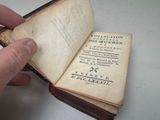 someone is holding an old book open to show it ' s pages