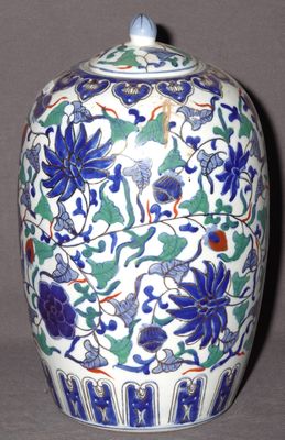 un vase bleu et blanc orné de fleurs et de feuilles