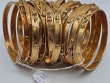 a close up of a stack of gold bangles on a white surface