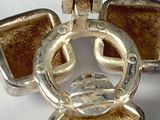 a silver cross with a brown stone in the center