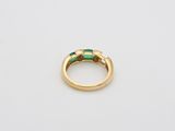 a close up of a gold ring with a green stone