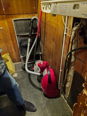 un homme debout dans une pièce, avec un sac rouge