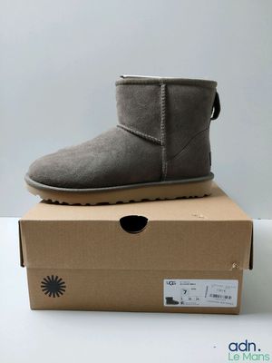 une paire de bottes Ugg grises posées sur une boîte en carton