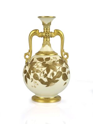 a white and gold vase with a gold handle on a white surface