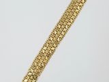 a close up of a gold bracelet on a white surface