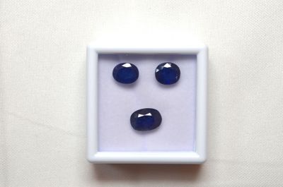 un gros plan sur trois saphirs bleus dans un écrin blanc
