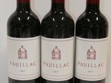 three bottles of red wine are lined up on a table