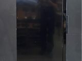 an image of a black refrigerator against a gray wall
