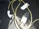 a cell phone hooked up to a yellow cord in the trunk of a car
