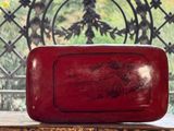une vieille boîte rouge posée sur une table près d'une fenêtre