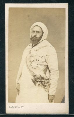 une vieille photo d'un homme barbu vêtu d'une tenue blanche
