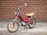 a small red motorcycle parked in front of a brick wall