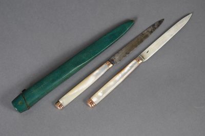 trois types de couteaux différents posés sur une table, avec un couteau au milieu