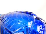 un vase en verre bleu orné d'un motif de feuilles
