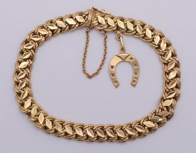 un gros plan sur un bracelet à chaîne en or orné d'une breloque en forme de fer à cheval