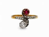 gros plan d'une bague en or avec une pierre rouge et des diamants