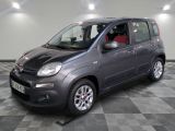 La petite voiture grise est garée dans le garage, sur le sol à carreaux.