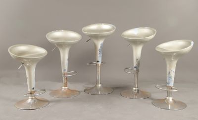 quatre tabourets en plastique blanc placés les uns à côté des autres sur une table