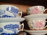 Plusieurs tasses et soucoupes sont posées sur une étagère dans un vaisselier