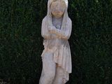 a statue of a woman standing in front of a hedge