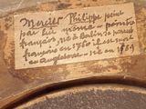 a plaque on the back of a vase with writing on it