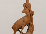une sculpture en bois représentant un homme sur un scooter sur lequel est perché un oiseau