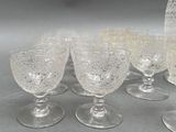six wine glasses and a pitcher sitting on a table