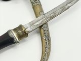 a very old dagger with a black handle on a white surface