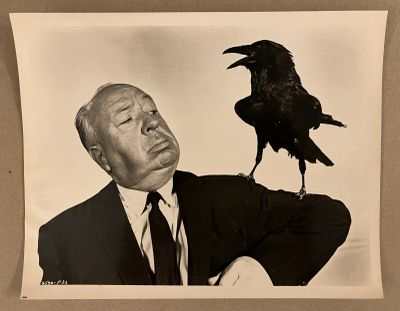 photographie en noir et blanc d'un homme en costume avec un corbeau sur l'épaule