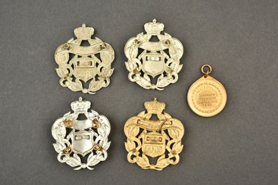 quatre insignes en or et en argent et une pièce de monnaie