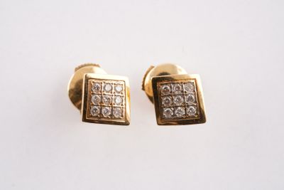 une paire de boucles d'oreilles en or et diamants posées sur une surface blanche