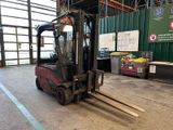 a forklift in a warehouse with pallets in the foreground