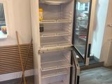 an open refrigerator with a broom next to it