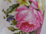 a white vase with pink and yellow flowers painted on it