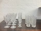 several glasses and a bucket on a wooden table with a clock in the background