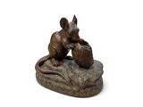 statue représentant une souris assise sur un rocher, tenant un panier de pommes