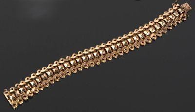 gros plan d'un bracelet en or sur une surface noire