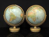 une paire de globes sur un socle posé sur une surface noire avec reflet