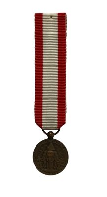 une vieille médaille ornée d'un ruban rouge et blanc sur fond blanc