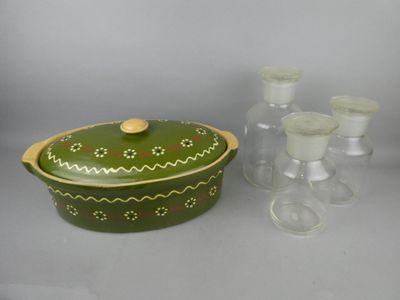 a green casserole with a wooden lid and a set of glasses